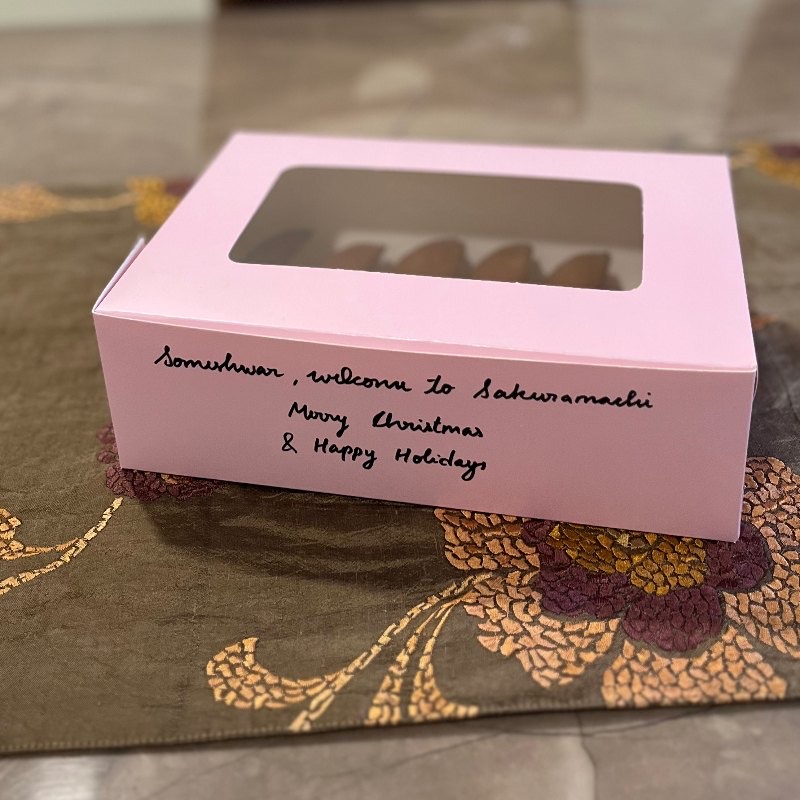 A pink sakuramachi bakery box, labelled by hand