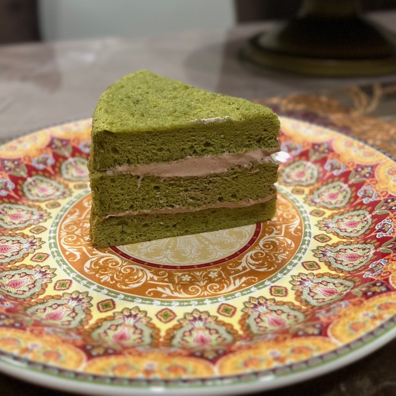 A slice of matcha layer cake on a patterned plate